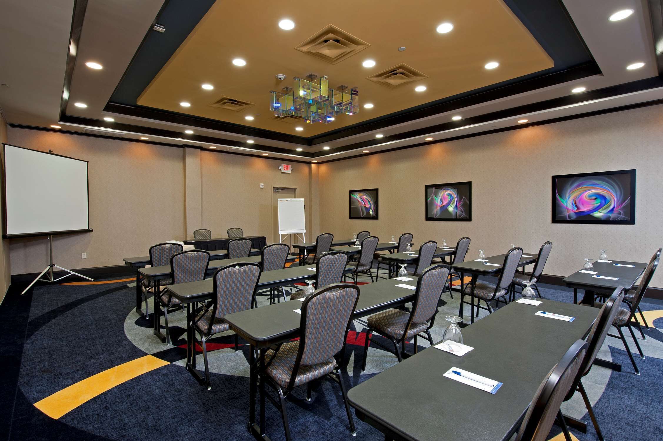 A conference room with tables and chairs, a projector, and a whiteboard.