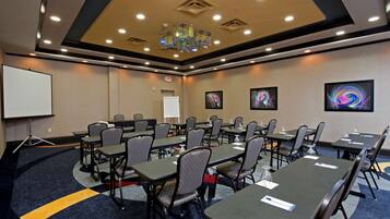 A conference room with tables and chairs, a projector, and a whiteboard.