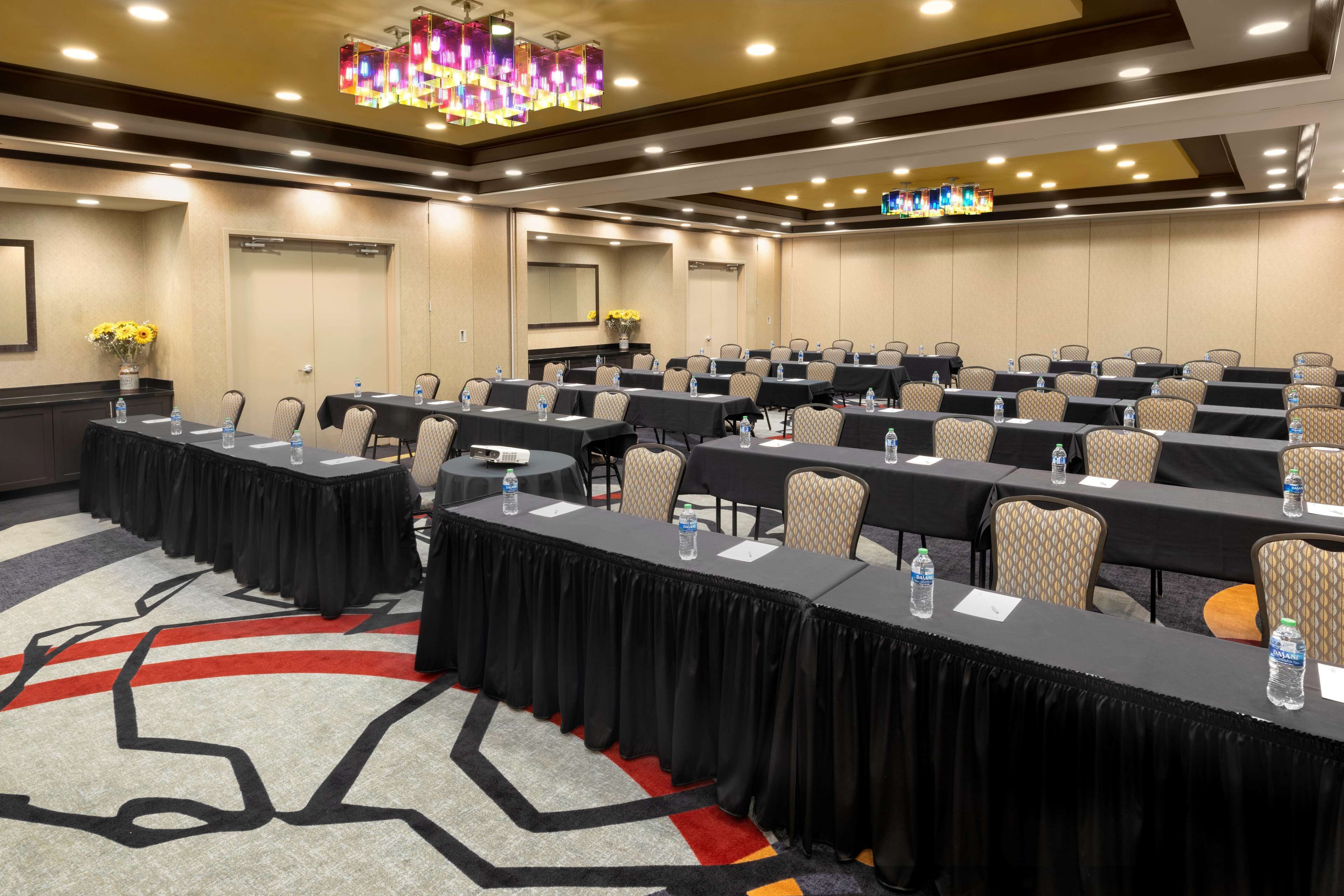 A conference room with multiple tables, chairs, and a chandelier.