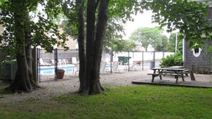A fenced backyard with a pool, picnic table, and trees. - Mariner Motel (Falmouth)