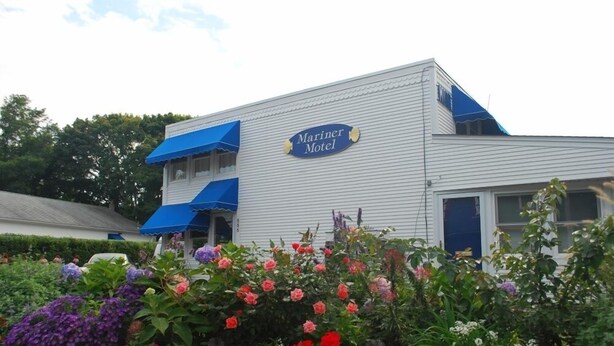 A building with a sign reading "Mariner Motel" and a garden with various flowers in front. - Mariner Motel (Falmouth)