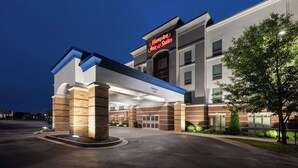 A Hampton Inn & Suites hotel entrance with a clear entrance, brick facade, and illuminated signage.