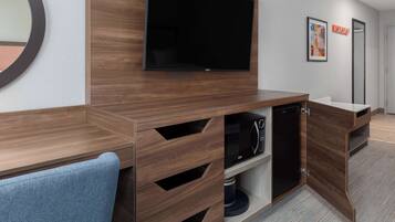 Une salle de bain moderne avec un meuble-lavabo en bois, un four à micro-ondes encastré et un grand miroir.