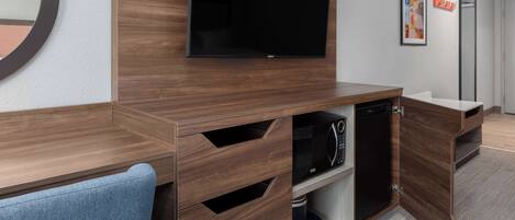 A modern bathroom with a wooden vanity, a built-in microwave, and a large mirror.