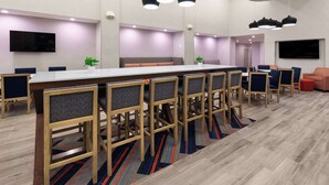 A modern meeting room with a long table, multiple chairs, and a television screen.