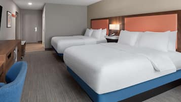 A hotel room with two beds, a desk, and a chair.
