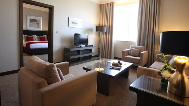 A hotel room with a bed, a television, a coffee table, two armchairs, a sofa, and a lamp. - Ramada by Wyndham Abu Dhabi Downtown (Abu Dhabi)