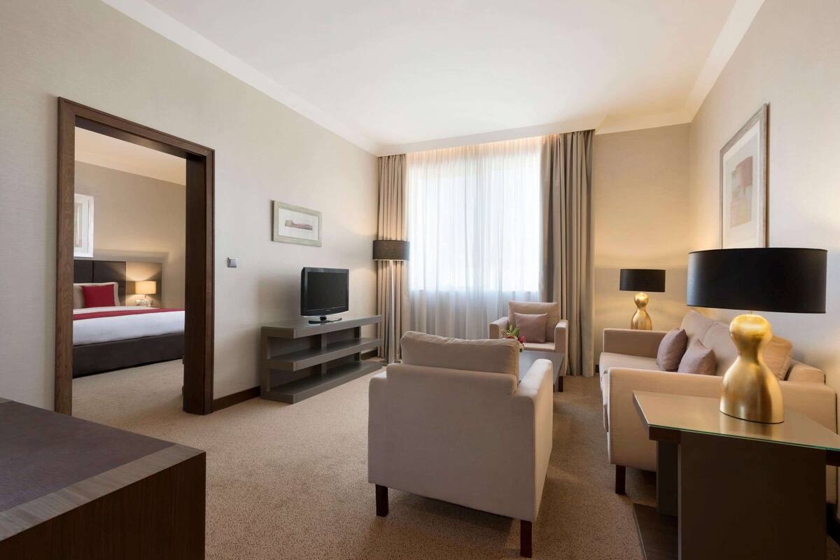 Ein Hotelzimmer mit einem Bett, zwei Sofas, einem Fernseher und einem Schreibtisch.