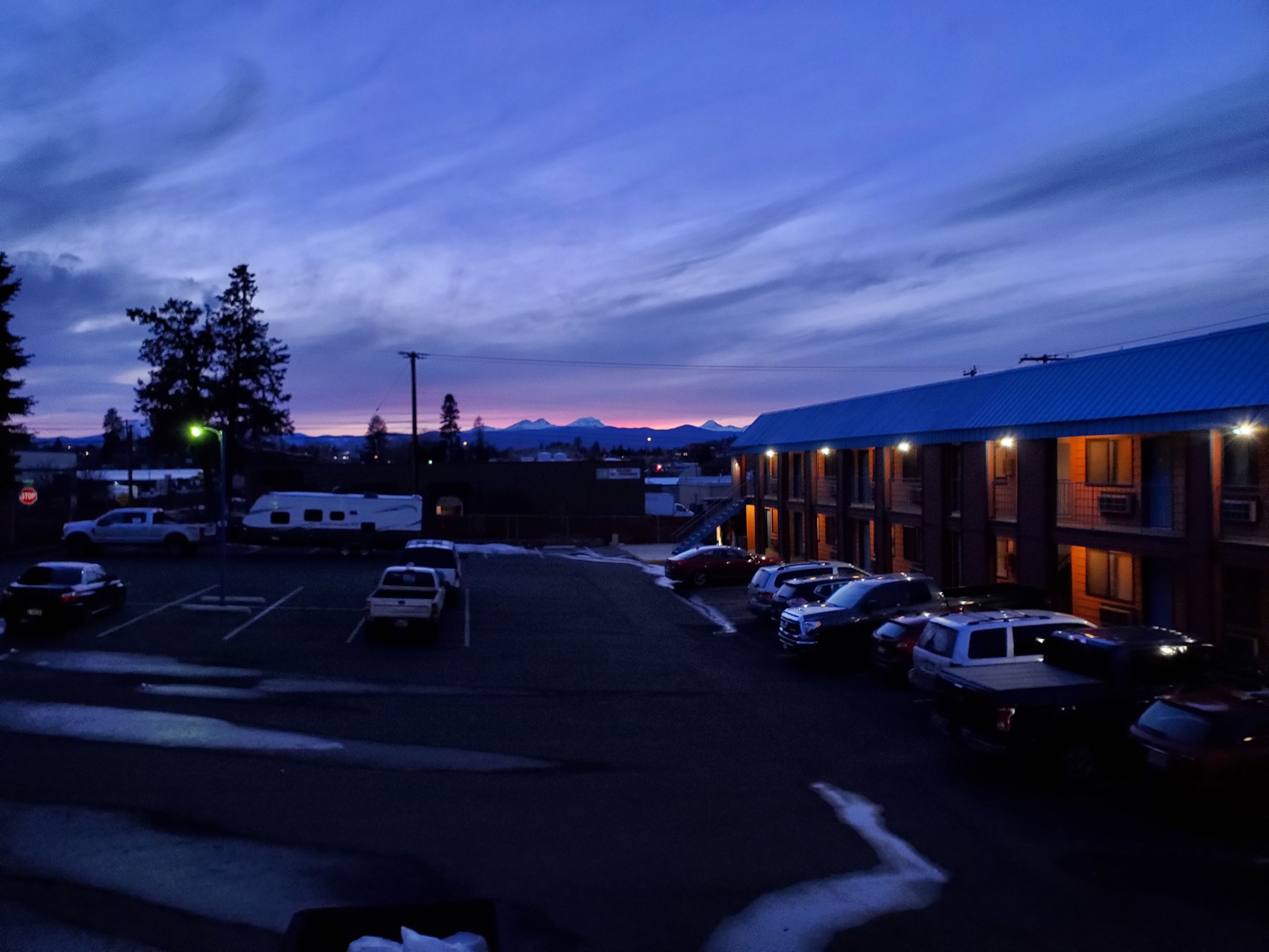A parking lot with several cars and a building with a blue roof.