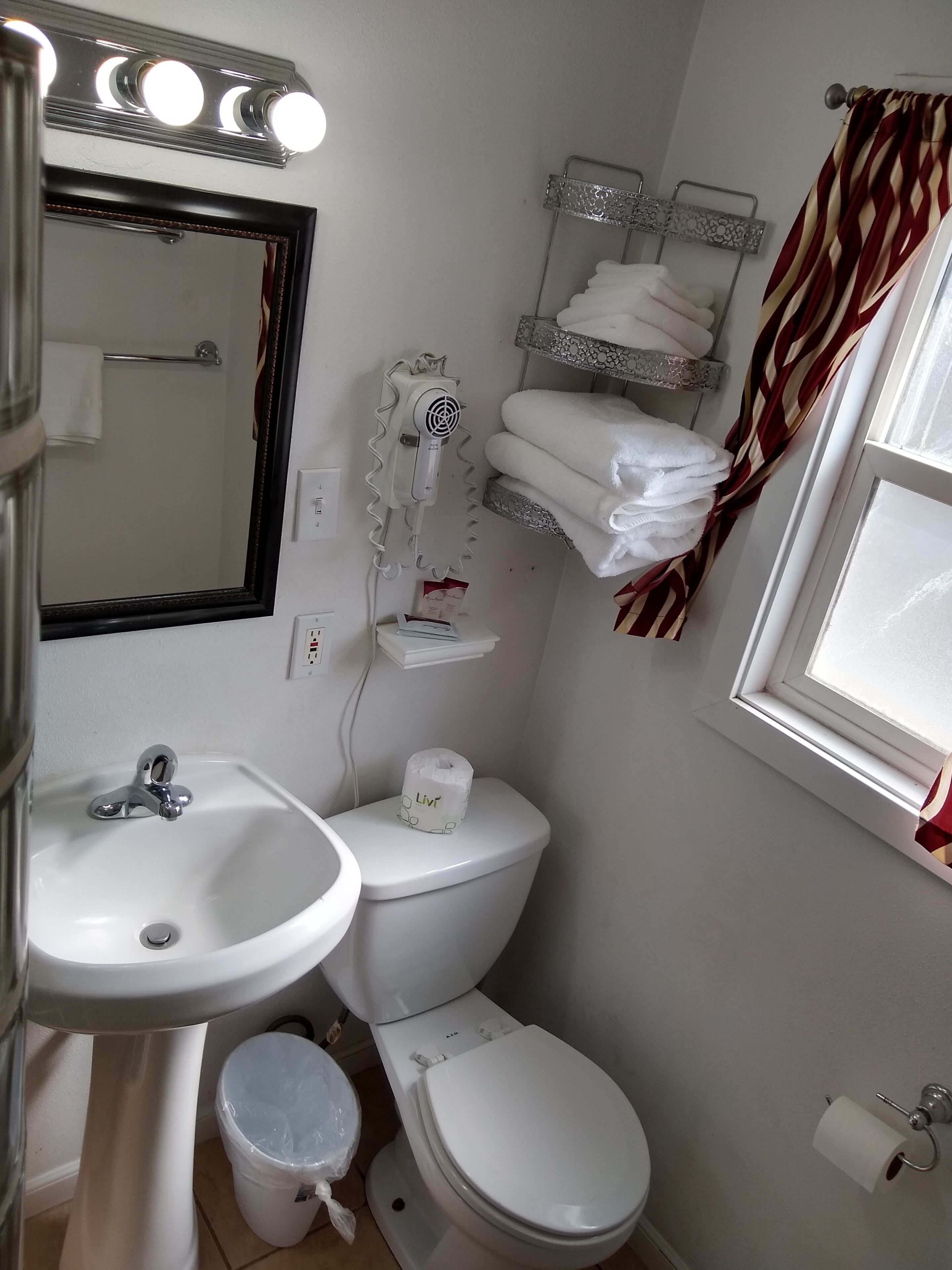 A bathroom with a sink, mirror, toilet, and a towel rack.