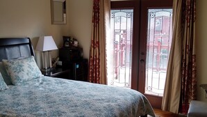 Un dormitorio con cama, mesita de noche, lámpara, cómoda y ventana con cortinas.