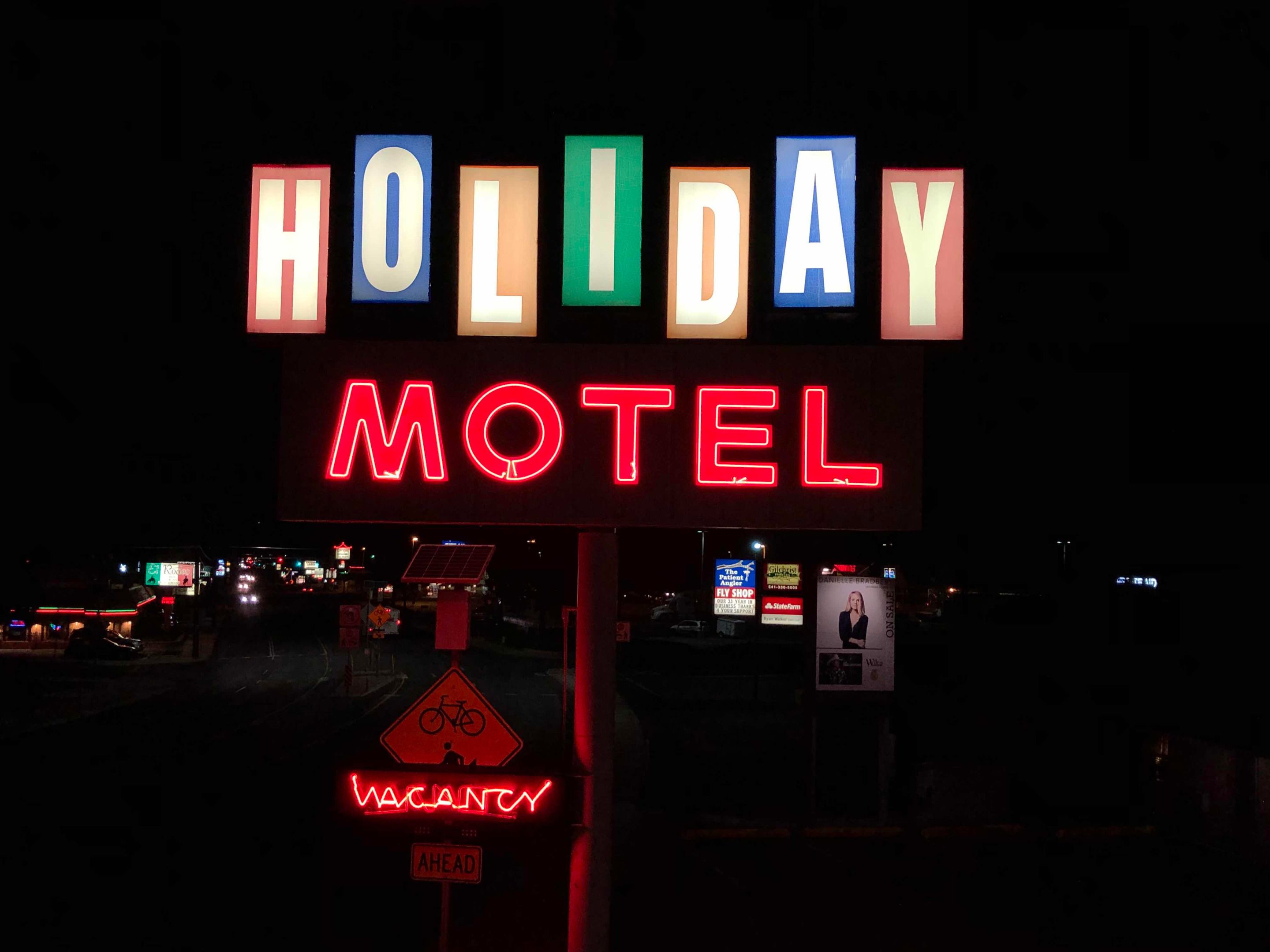 Un letrero de neón para el Holiday Motel, con un anuncio de habitaciones disponibles debajo.