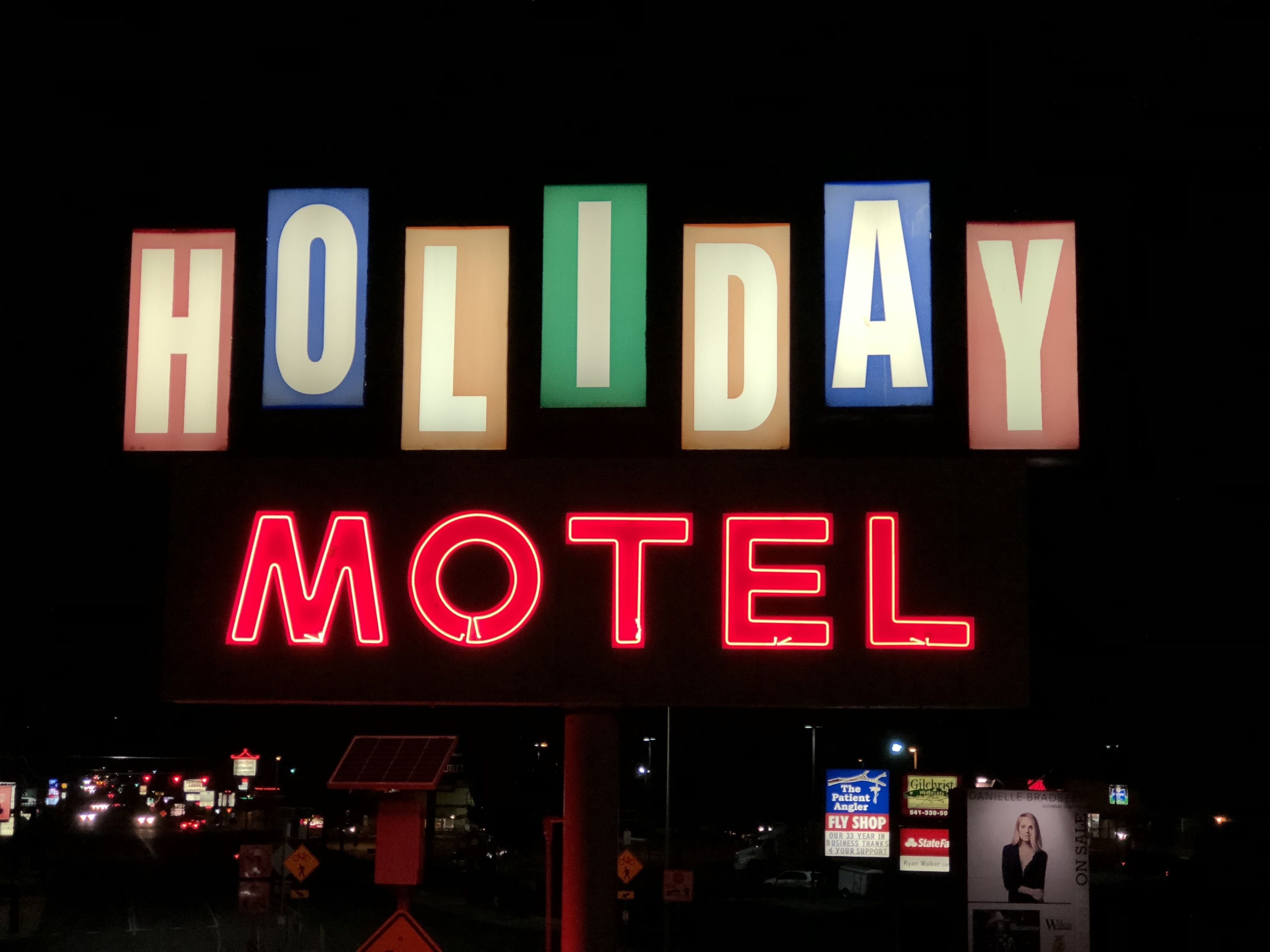A neon sign for a motel with the words "HOLIDAY" and "MOTEL" in colorful letters.