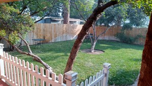 Un patio trasero con valla de madera, un árbol y una mesa.