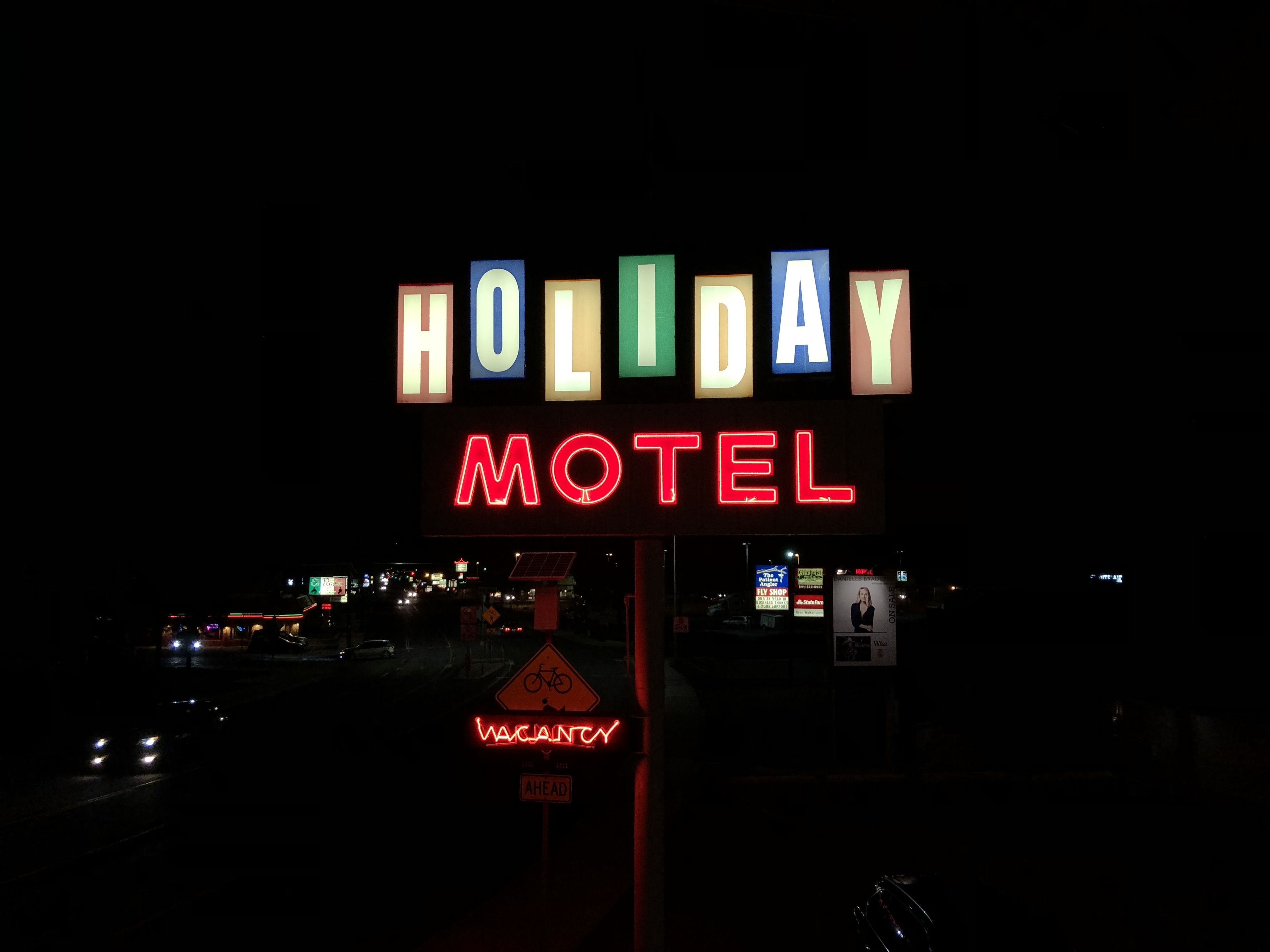 Un letrero de neón para el Holiday Motel con un anuncio de habitaciones disponibles debajo.