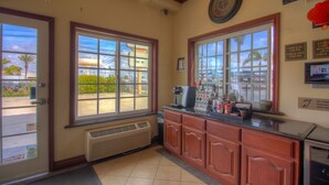 A reception area with a counter, a coffee machine, and a view of a parking lot through large windows.