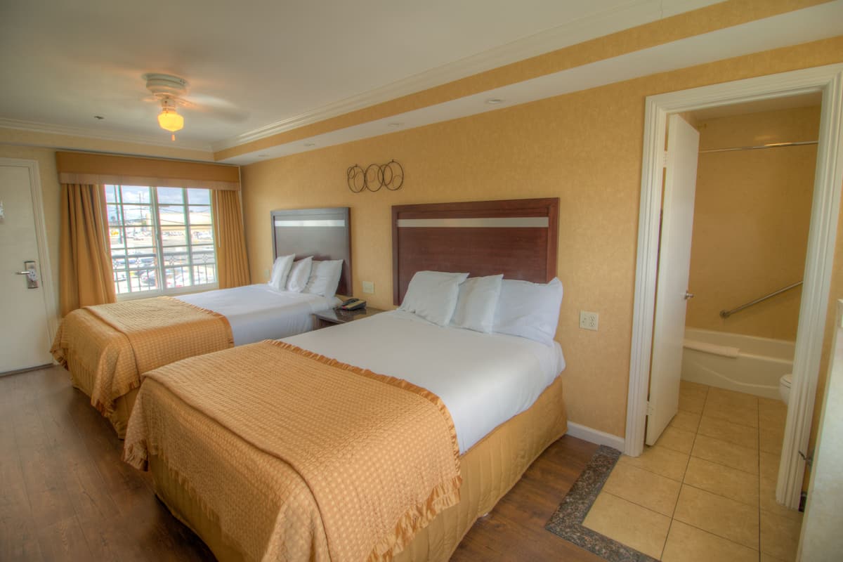 Une chambre d’hôtel avec deux lits, une salle de bain avec une baignoire et une fenêtre avec des rideaux.