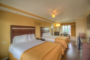 A hotel room with two beds, a desk, a mirror, and a window with curtains.