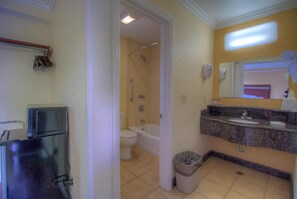 A bathroom with a toilet, bathtub, sink, and a trash can.