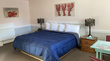 Une chambre à coucher avec un grand lit, deux tables de chevet avec des lampes, un fauteuil rouge et des œuvres d’art accrochées aux murs.