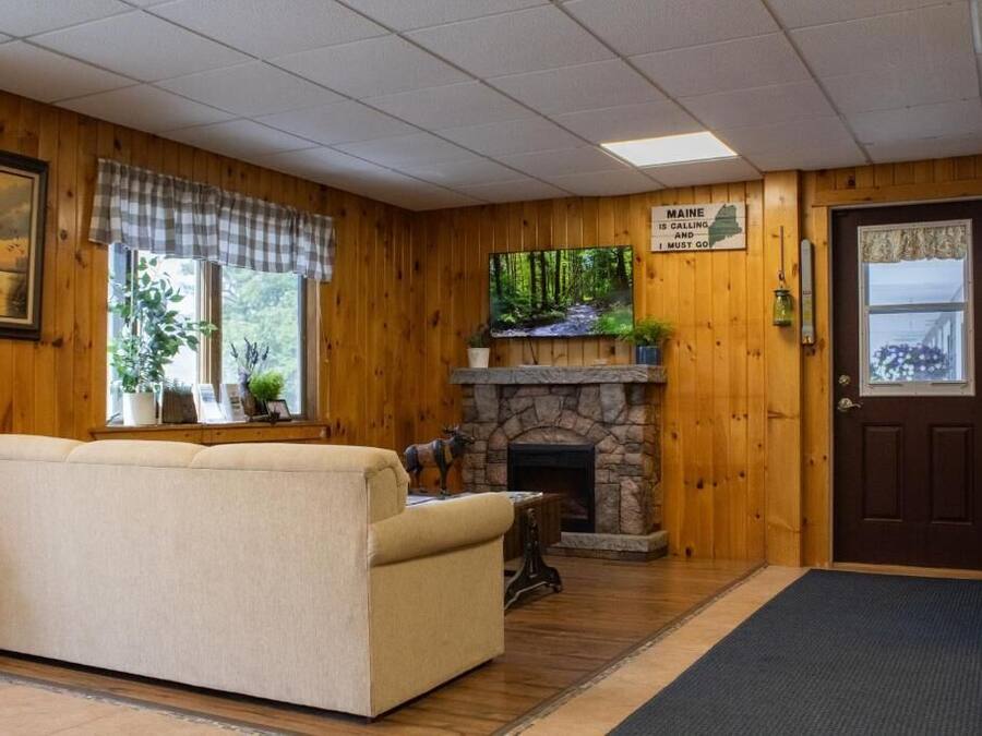A cozy room with a stone fireplace, a sofa, and a sign above the door.