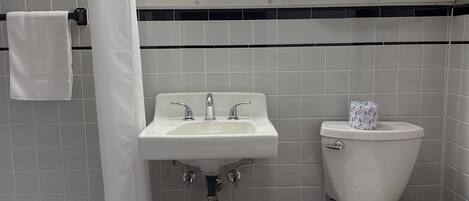 A bathroom with a sink, toilet, and bathtub. There are three lights above the mirror, and a towel rack with towels.