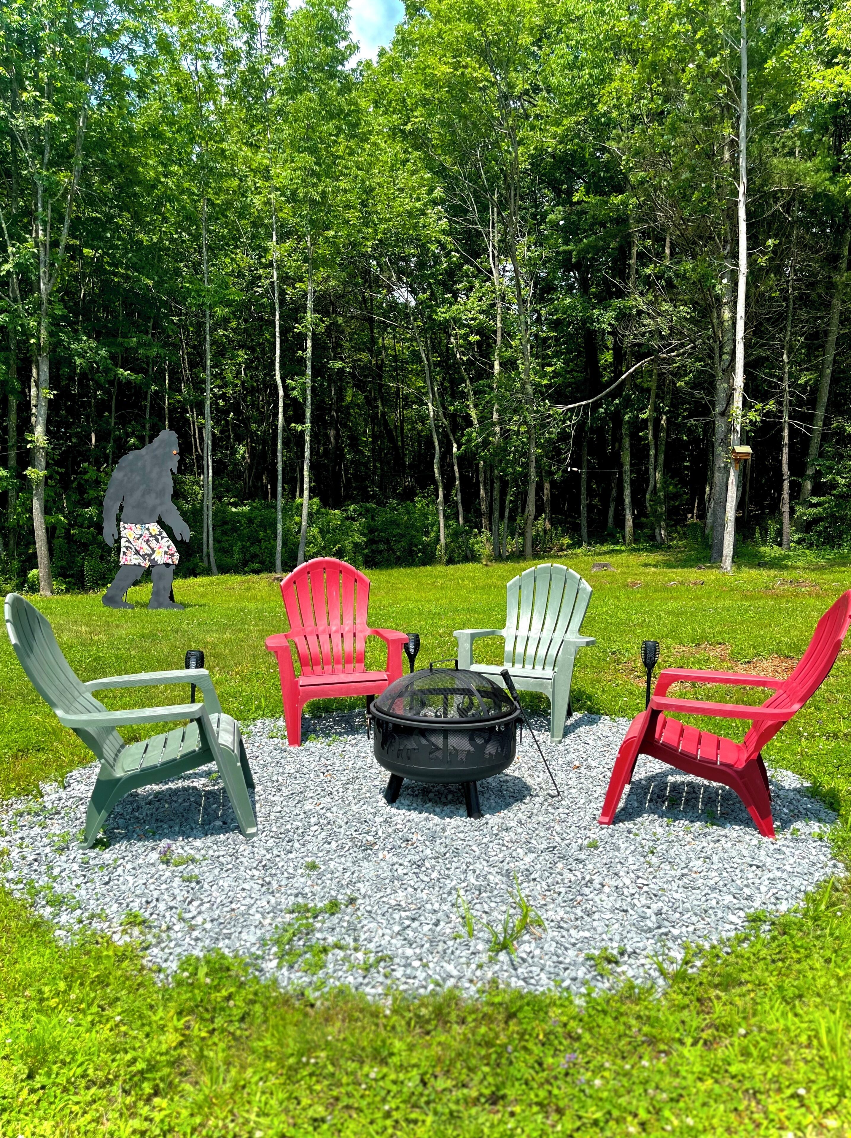Un giardino con un focolare, quattro poltrone Adirondack e una persona sullo sfondo.