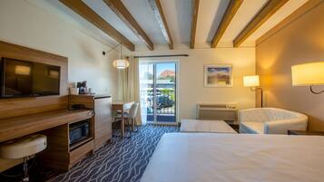 Une chambre d’hôtel équipée d’un lit, d’un bureau, d’une chaise, d’une télévision et offrant une vue sur l’extérieur.