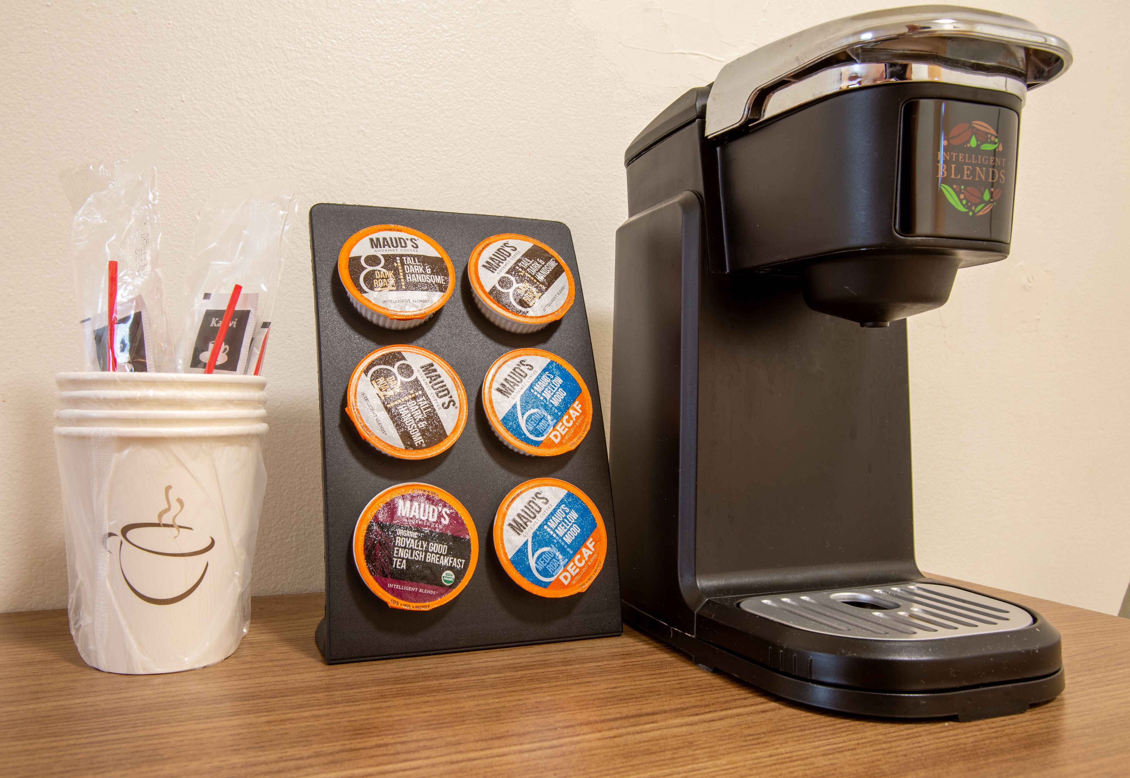 A coffee maker with a coffee pod holder and a mug with straws.