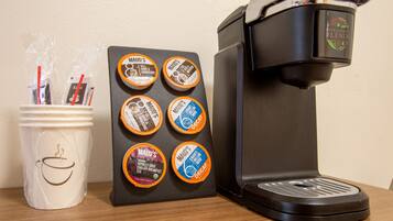 A coffee maker with a coffee pod holder and a mug with straws.
