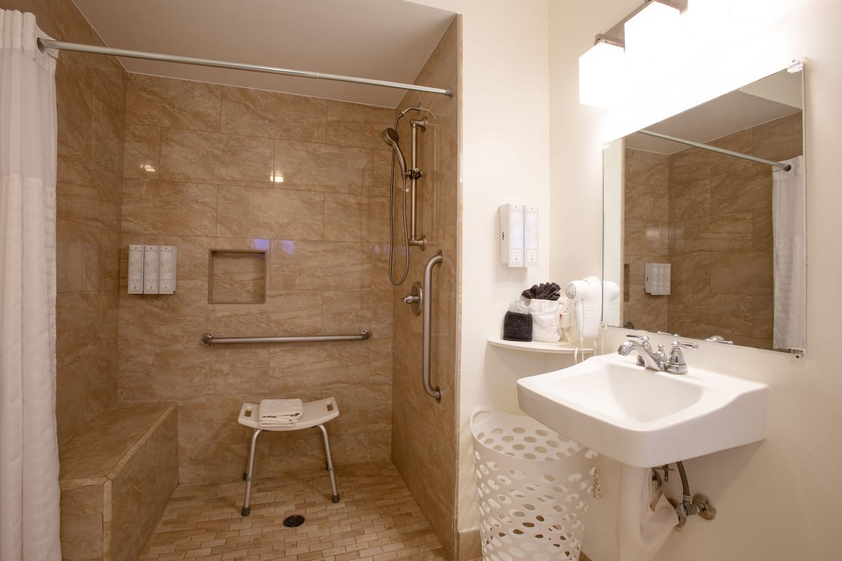 A bathroom with a shower, a sink, and a mirror.