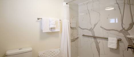 A bathroom with a toilet, a shower with a glass door, and a towel rack.