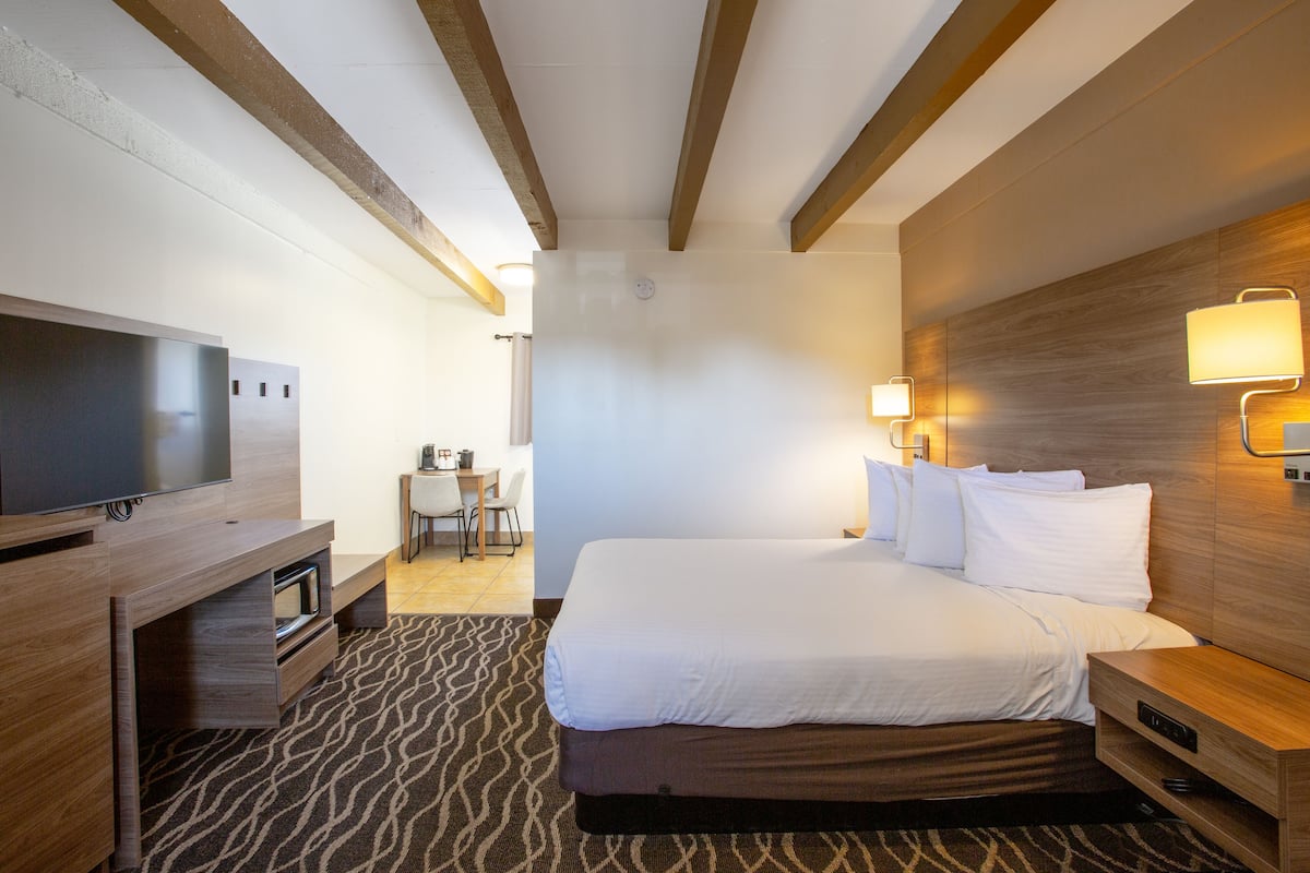 A hotel room with a bed, a TV, a desk, and a chair.
