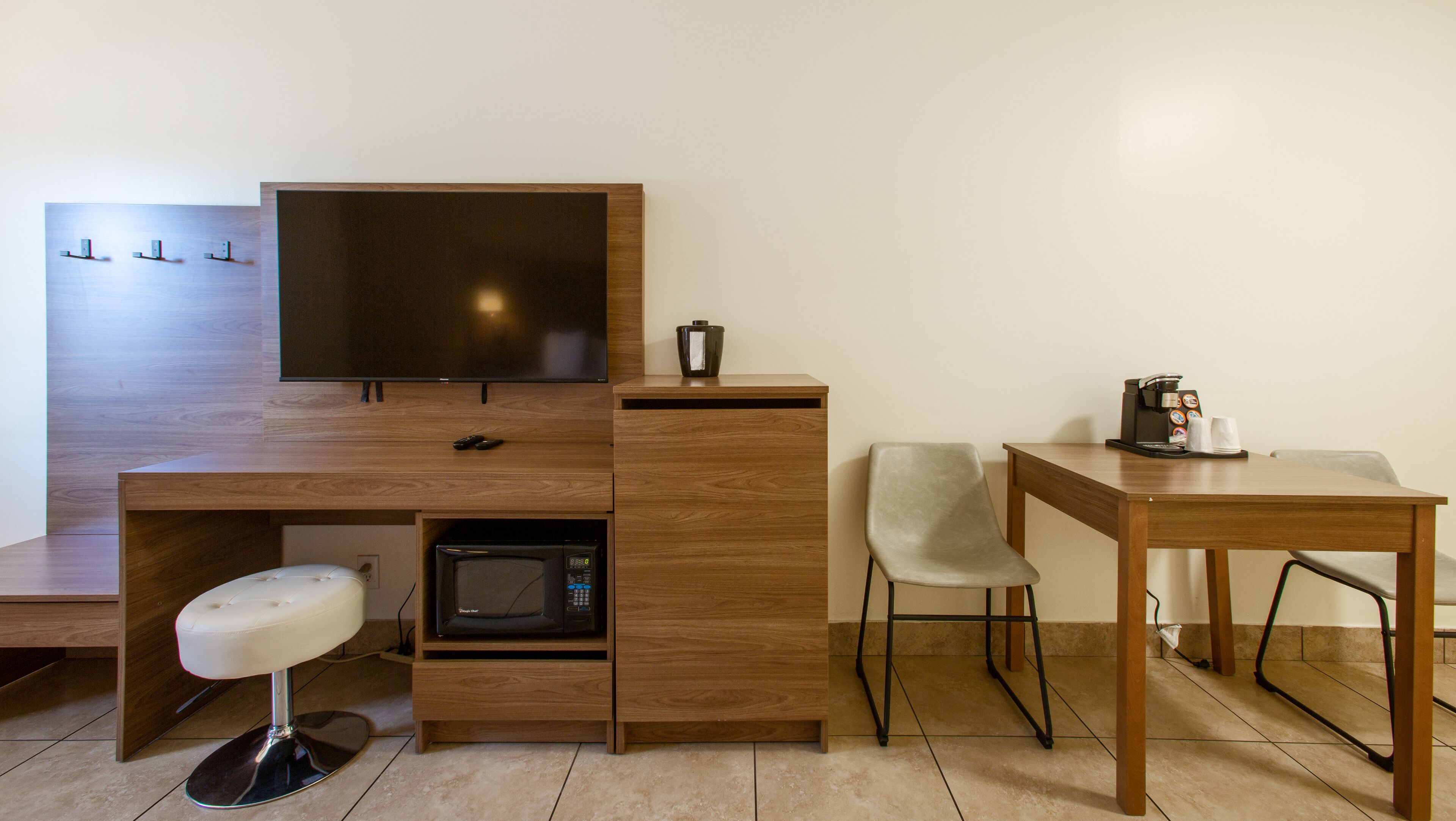 A compact kitchenette with a microwave, a coffee machine, and a small bar stool.