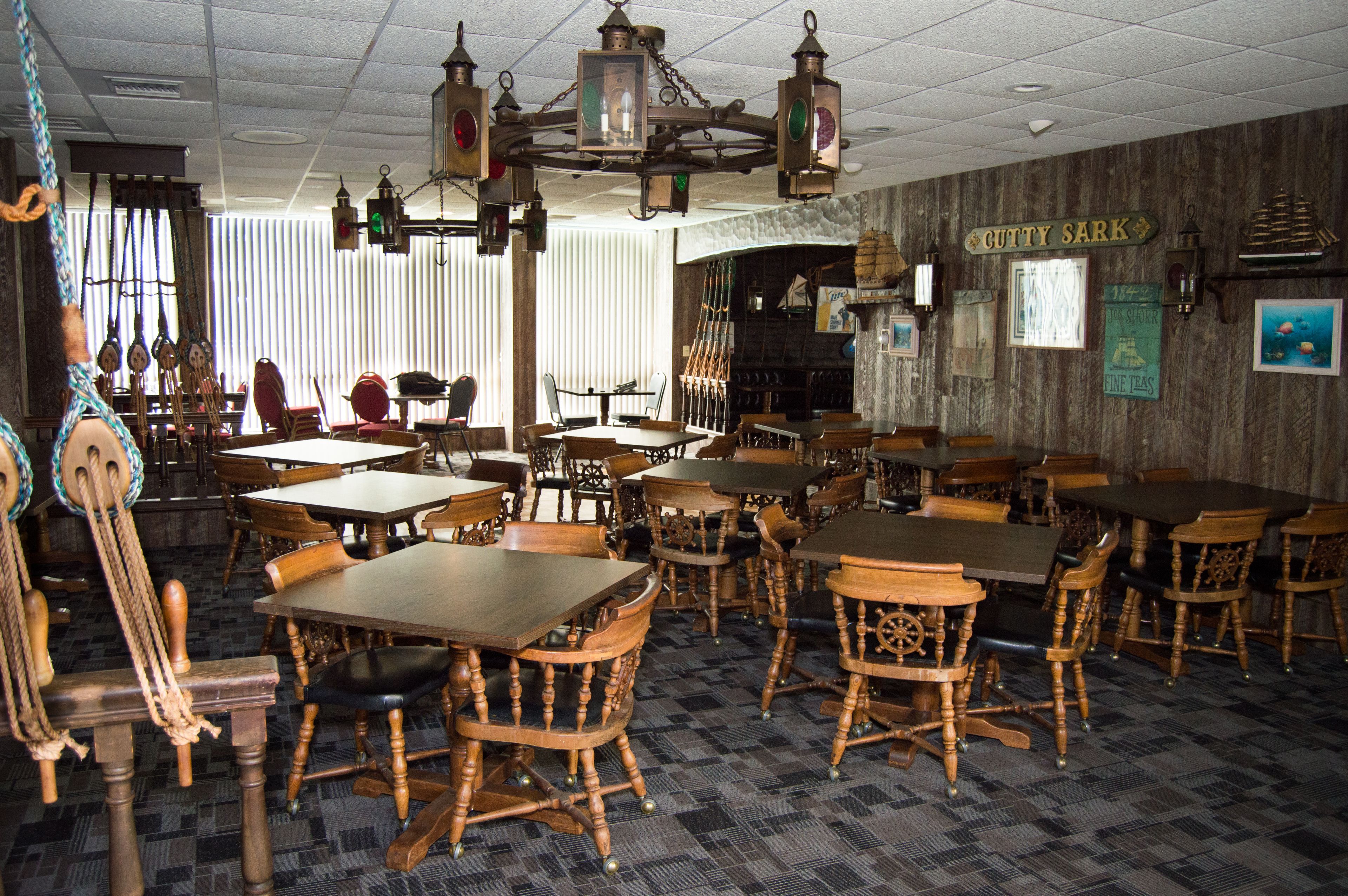A restaurant interior with wooden tables and chairs, a chandelier, and a sign reading "CUTTY SARK".