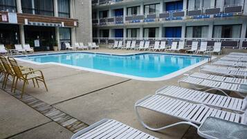 Une piscine avec des chaises longues et, au fond, un bâtiment doté de nombreux balcons.