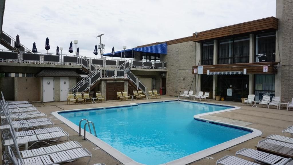 Ein Schwimmbecken mit Liegestühlen und einer Treppe, die zu einem Gebäude führt.