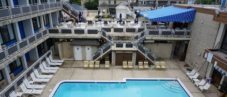A swimming pool with sun loungers and a covered seating area.
