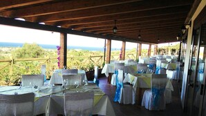 Un área de comedor al aire libre con mesas dispuestas para una comida, con vistas a un paisaje pintoresco.