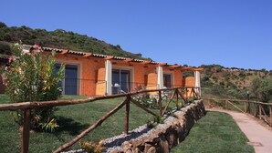 Un edificio con techo de tejas, un camino de piedra y una zona verde con plantas.