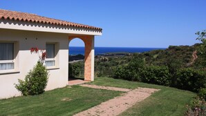 Una casa con techo de tejas, un arco y vista al mar.