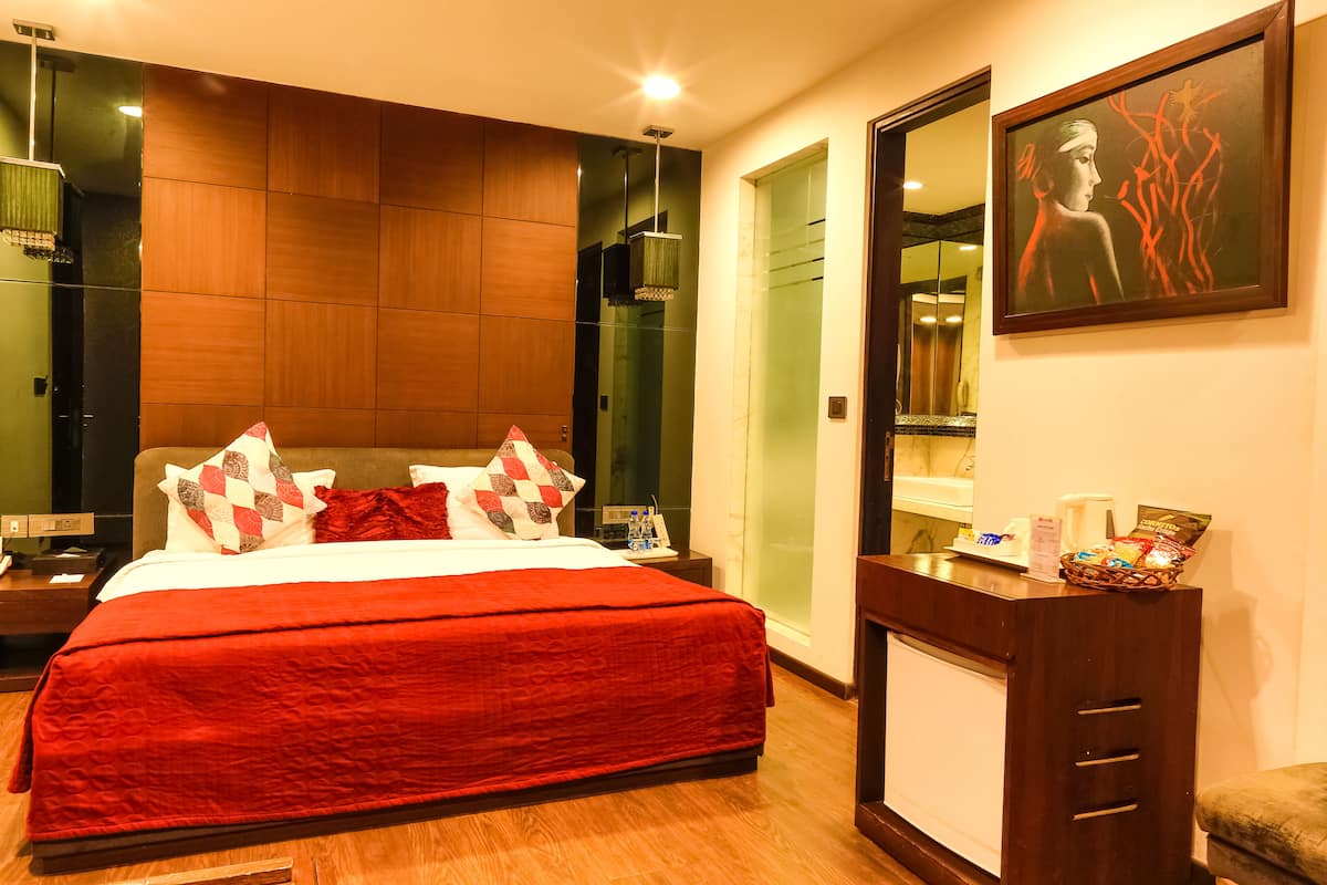 Una habitación de hotel moderna con una cama grande, paneles de madera, un espejo y un cuadro.