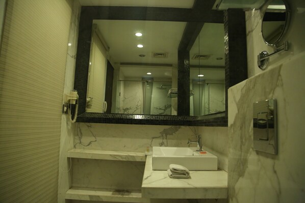 Un baño con un espejo grande, un lavamanos y una zona de ducha.