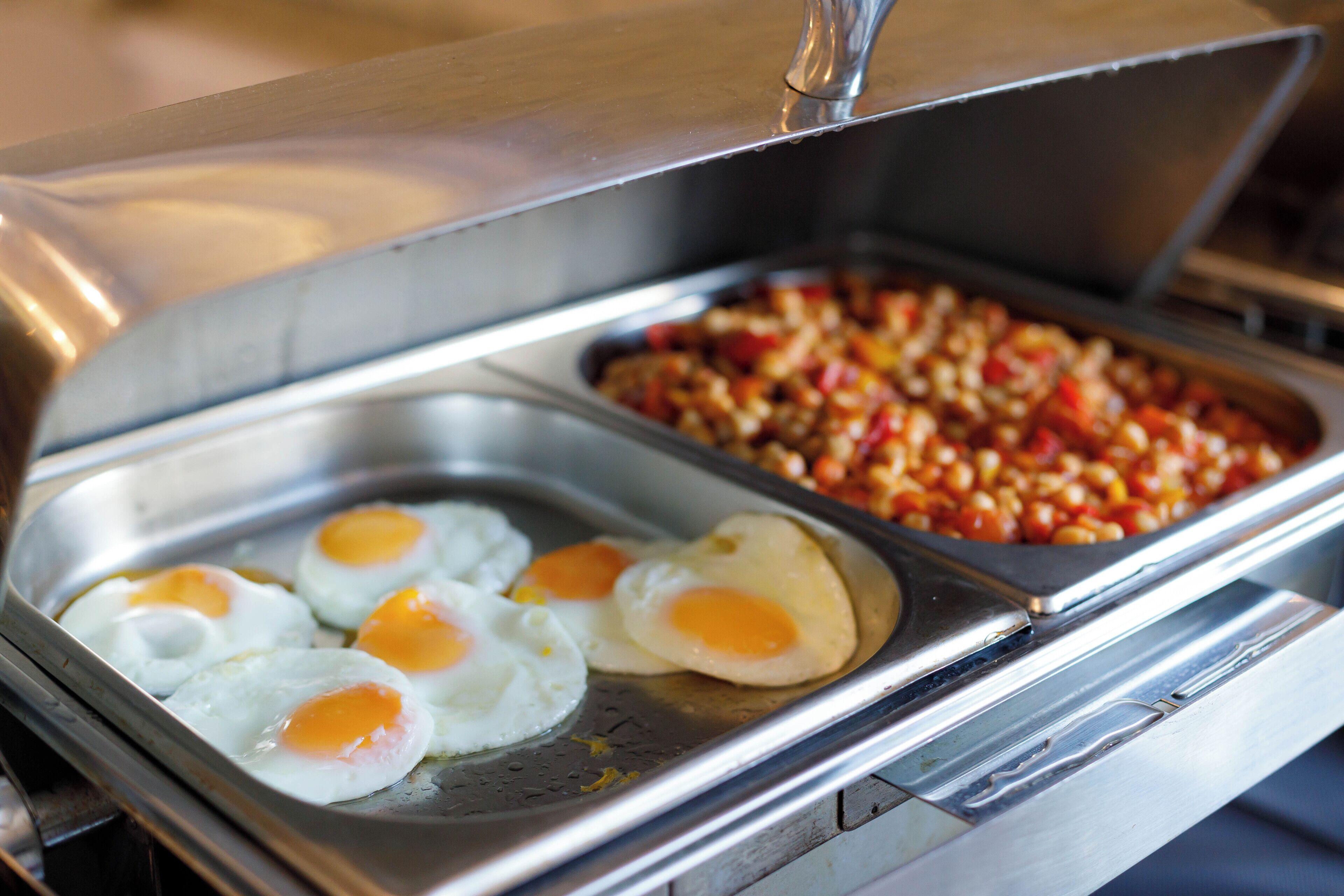 A buffet with cooked eggs and a dish of mixed vegetables.