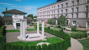 A courtyard with a fountain, white columns, and a building with multiple windows. - Hotel Lamberton (Ozarow Mazowiecki)