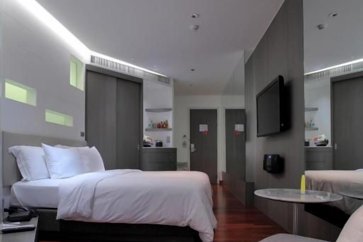 Una habitación de hotel moderna con una cama, un sofá, una mesita y un televisor.
