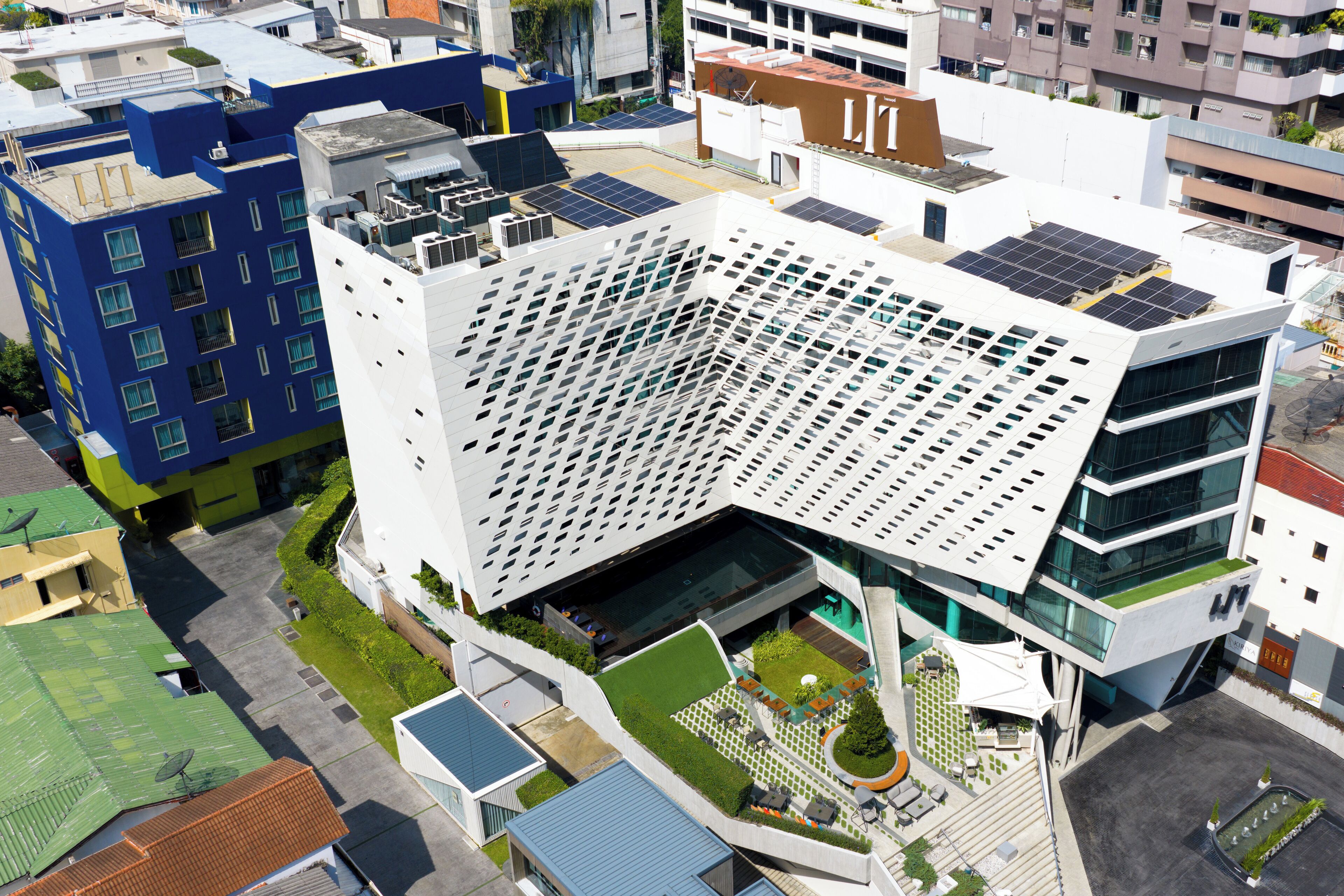 A modern building with a unique angular design, featuring a rooftop garden and solar panels.