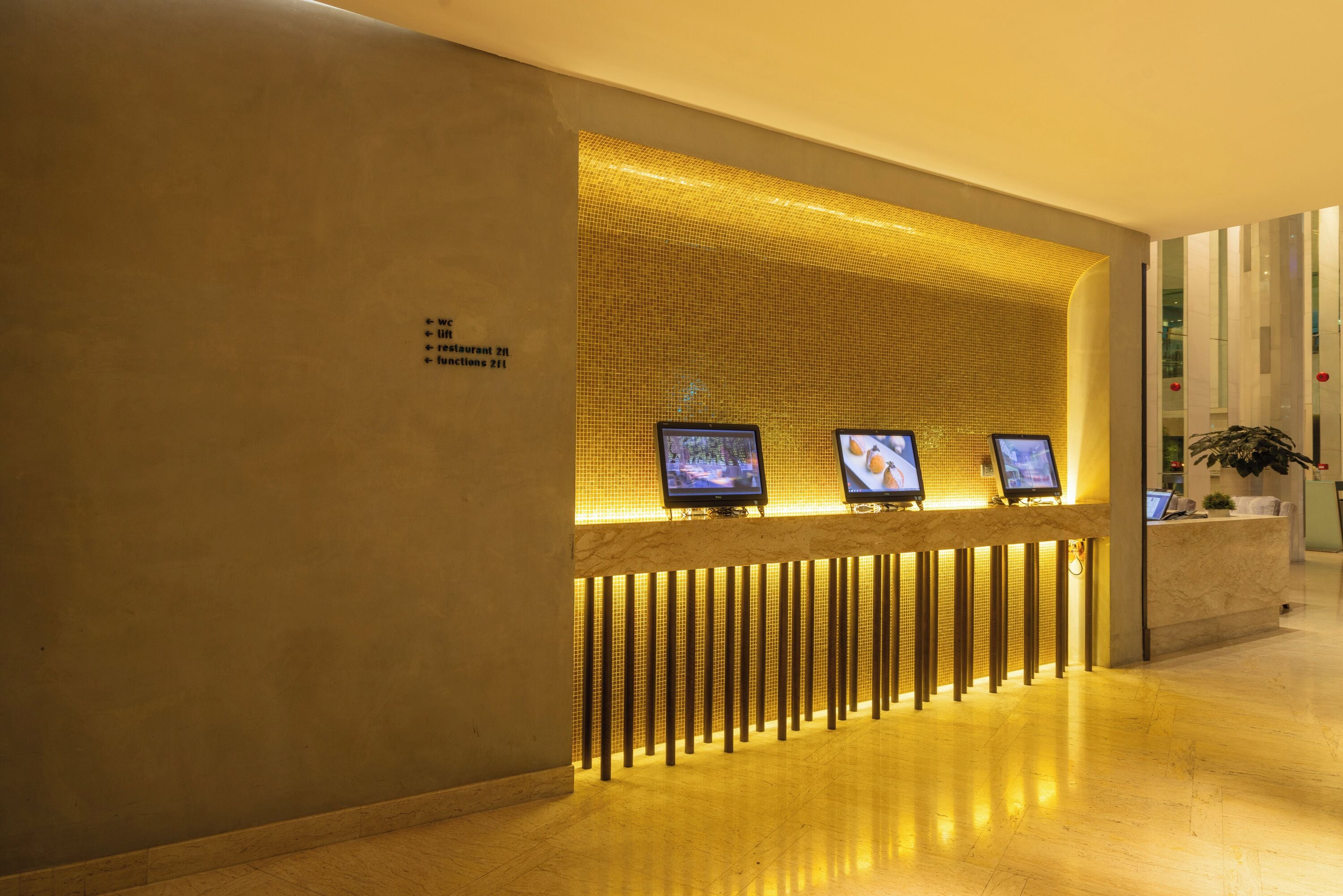 A reception area with a tiled wall, three monitors, and a reception desk.