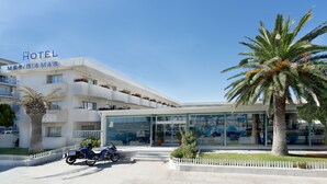 Un hôtel au design moderne, caractérisé par une façade en verre et un palmier en premier plan.