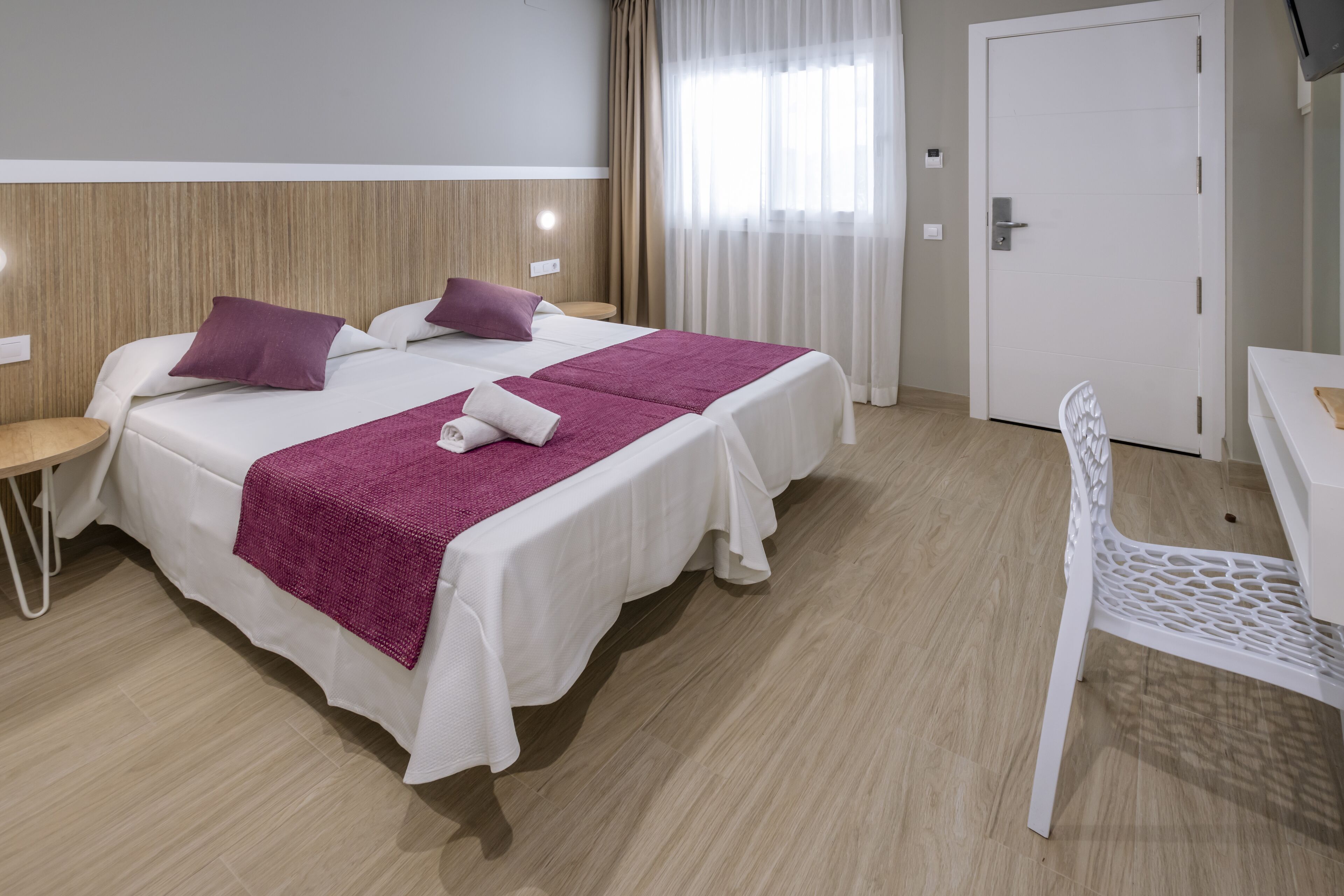 Habitación de hotel con dos camas, un escritorio y una silla.